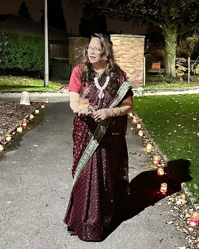 Neetu at Diwali, holding a lit diya, with lights along the path